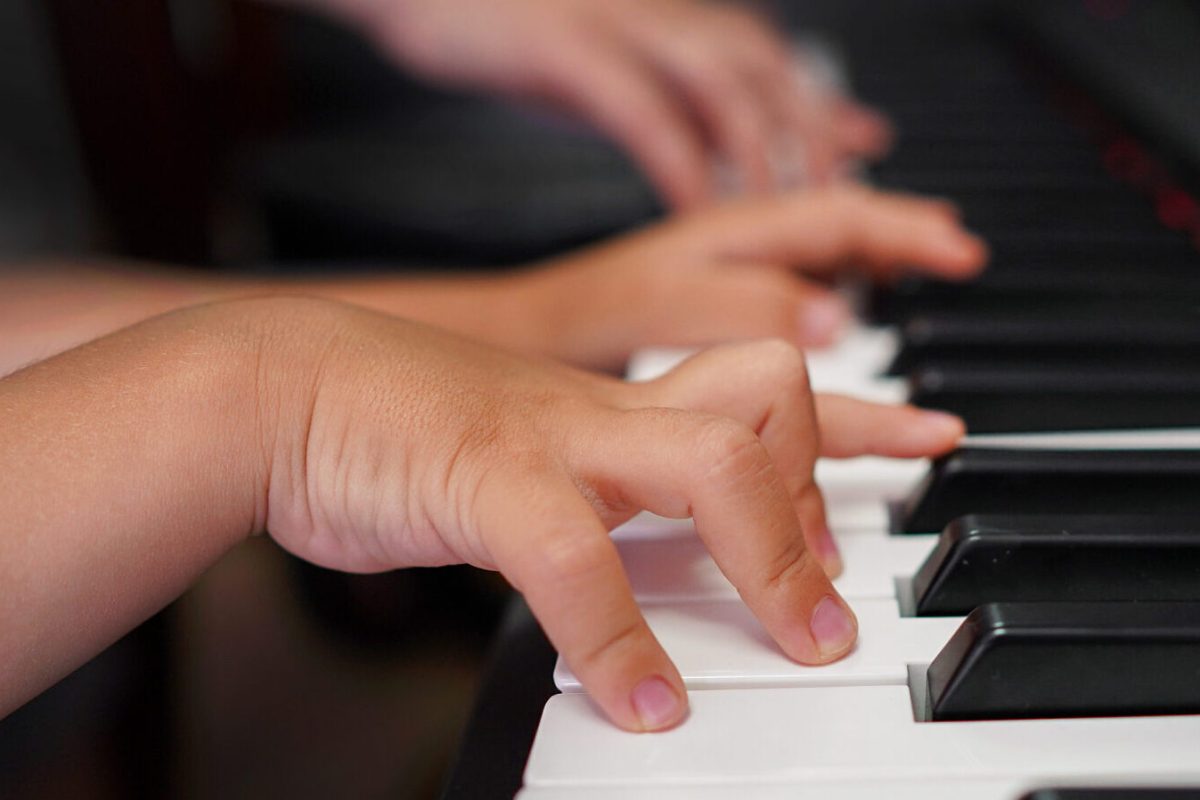Children's hands and teacher's hands on the piano keys. ?hildren's hands plays the piano, learning a lesson, black and white keys. Training on a synthesizer. Selective focus
